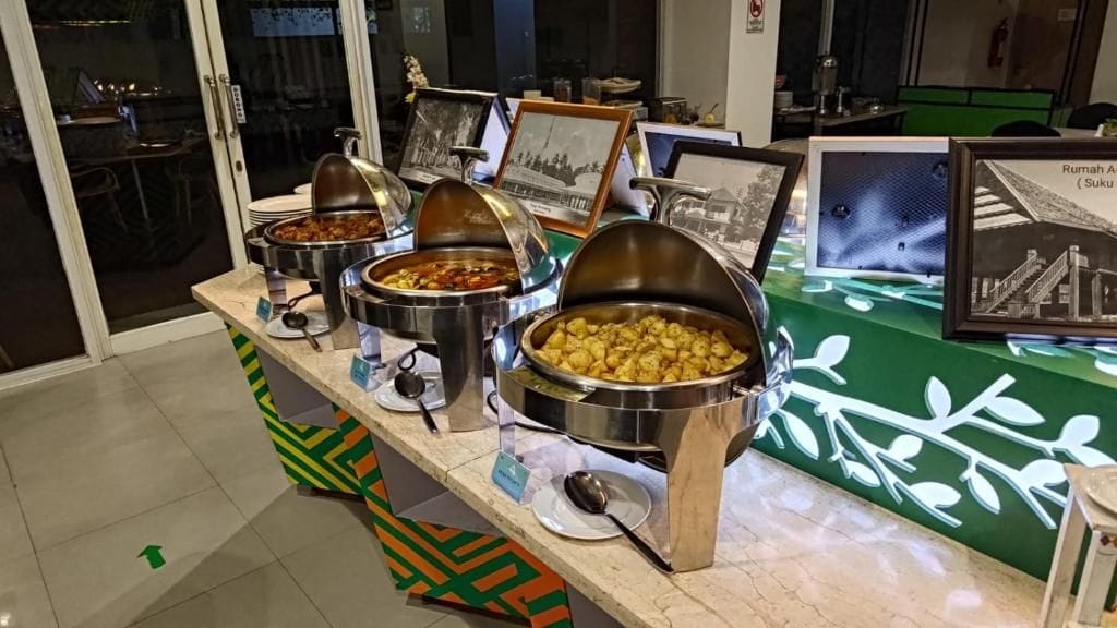 A buffet setup with various food containers and framed pictures on a counter.