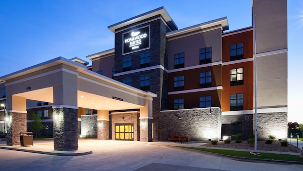 A hotel with a modern design, featuring a prominent entrance with a covered area and stone pillars.
