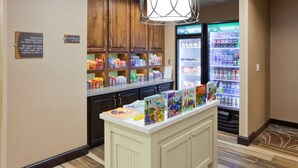 A hotel lobby with a reception desk, a refrigerator stocked with beverages, and a display of children's books.