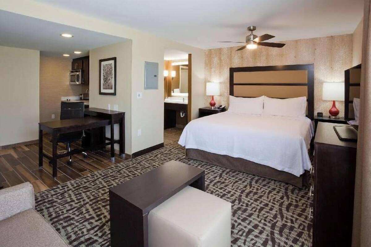 A hotel room with a bed, desk, chair, and a small table.