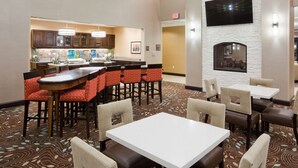 A hotel lobby with a bar area, seating arrangements, and a fireplace.