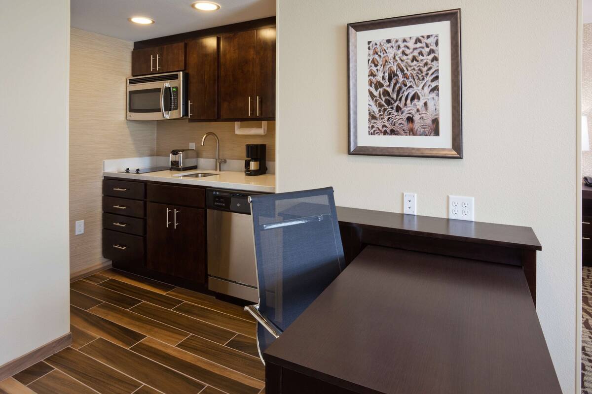 A modern kitchen with dark wood cabinets, stainless steel appliances, and a glass-fronted refrigerator.