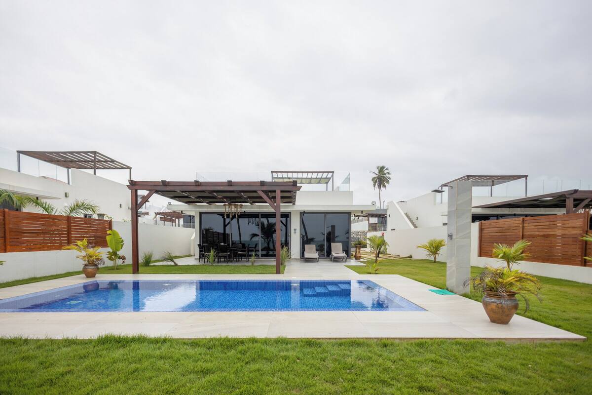 Ein modernes Haus mit Schwimmbad, überdachter Terrasse und gepflegtem Rasen.