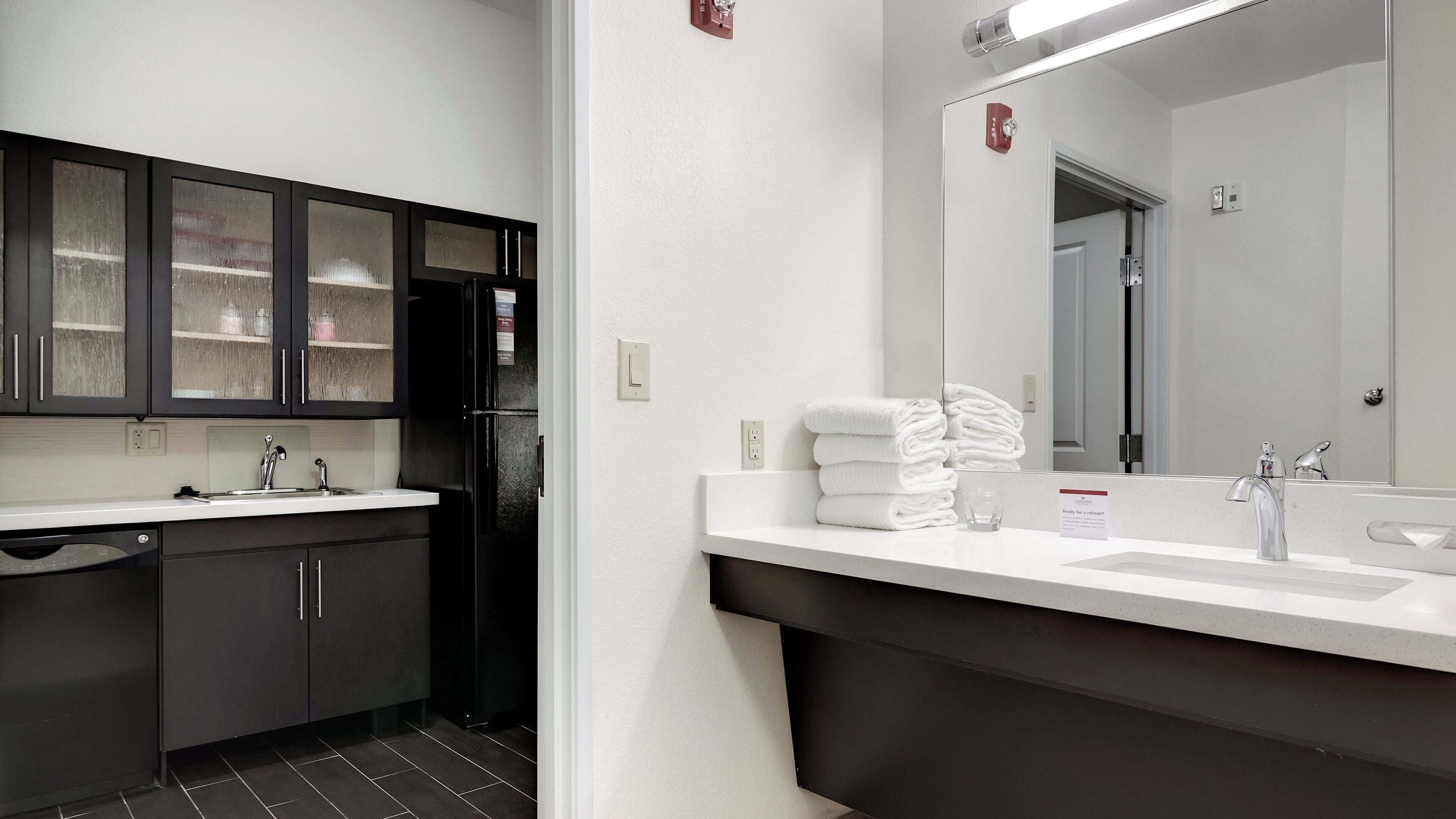 A modern bathroom with a large mirror, two sinks, and a black cabinet with glass doors.