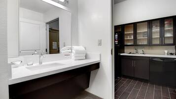 A modern bathroom with a double sink, a mirror, and a towel rack.