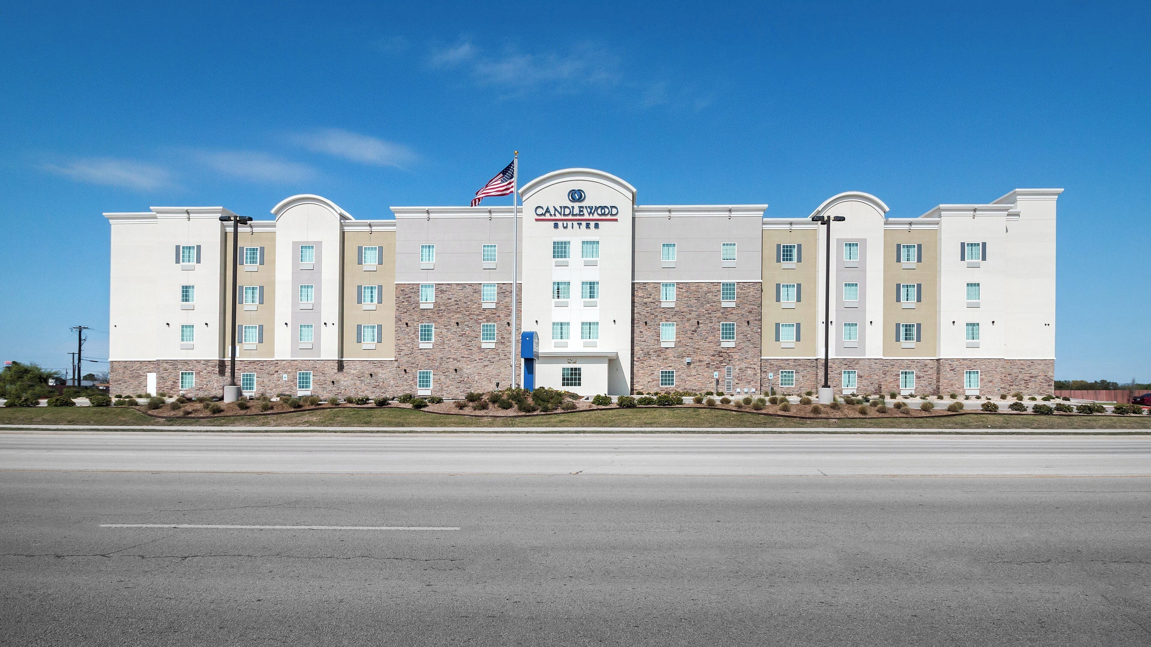 A multi-story hotel with a flat facade, a flag, and a sign indicating it is a Candlewood Suites.
