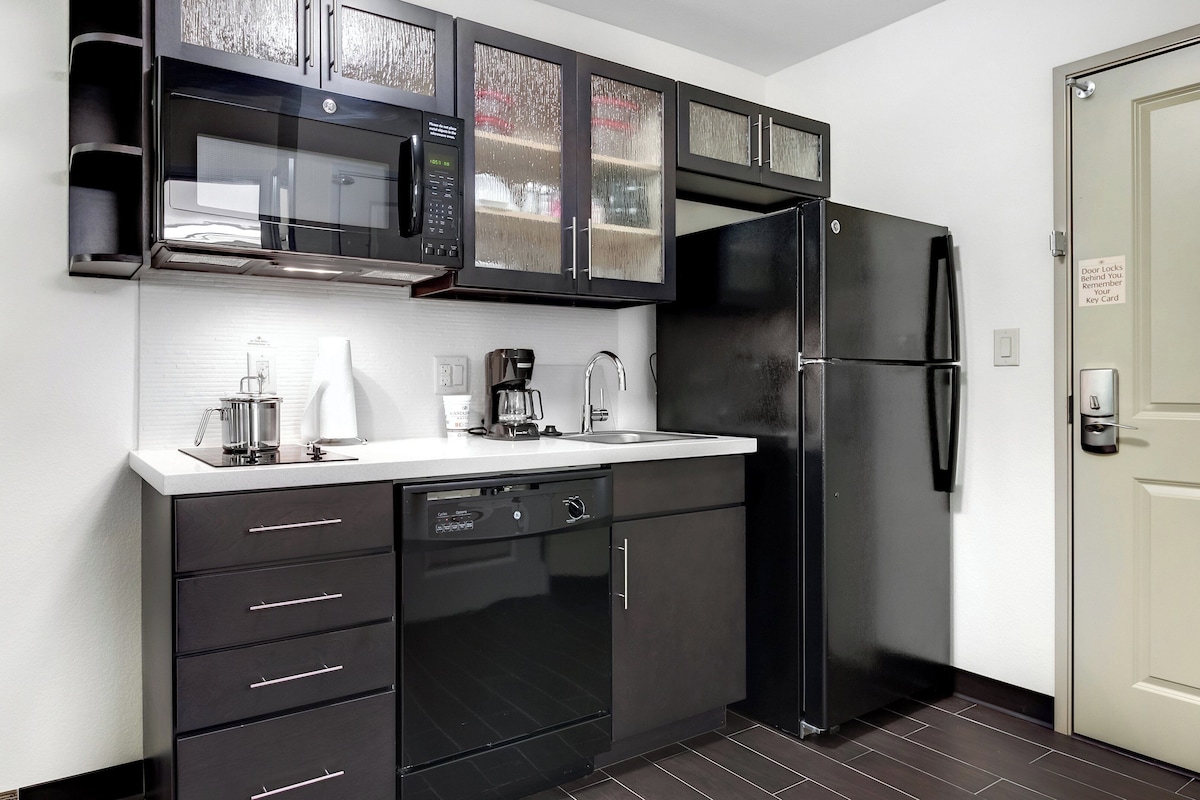 Una cocina con un refrigerador negro, cafetera y lavavajillas.