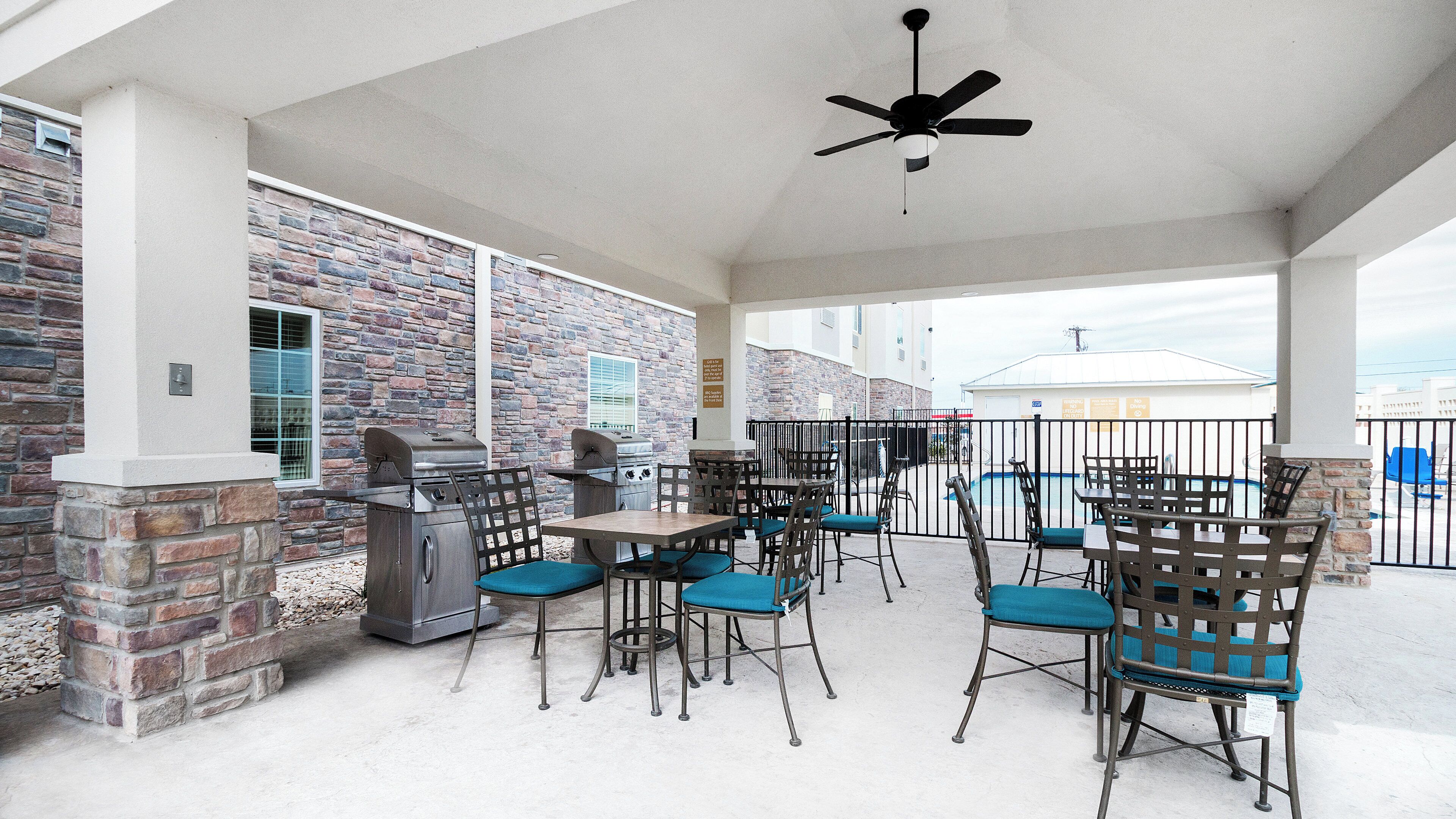 An outdoor patio with stone walls, a ceiling fan, and barbecue grills.