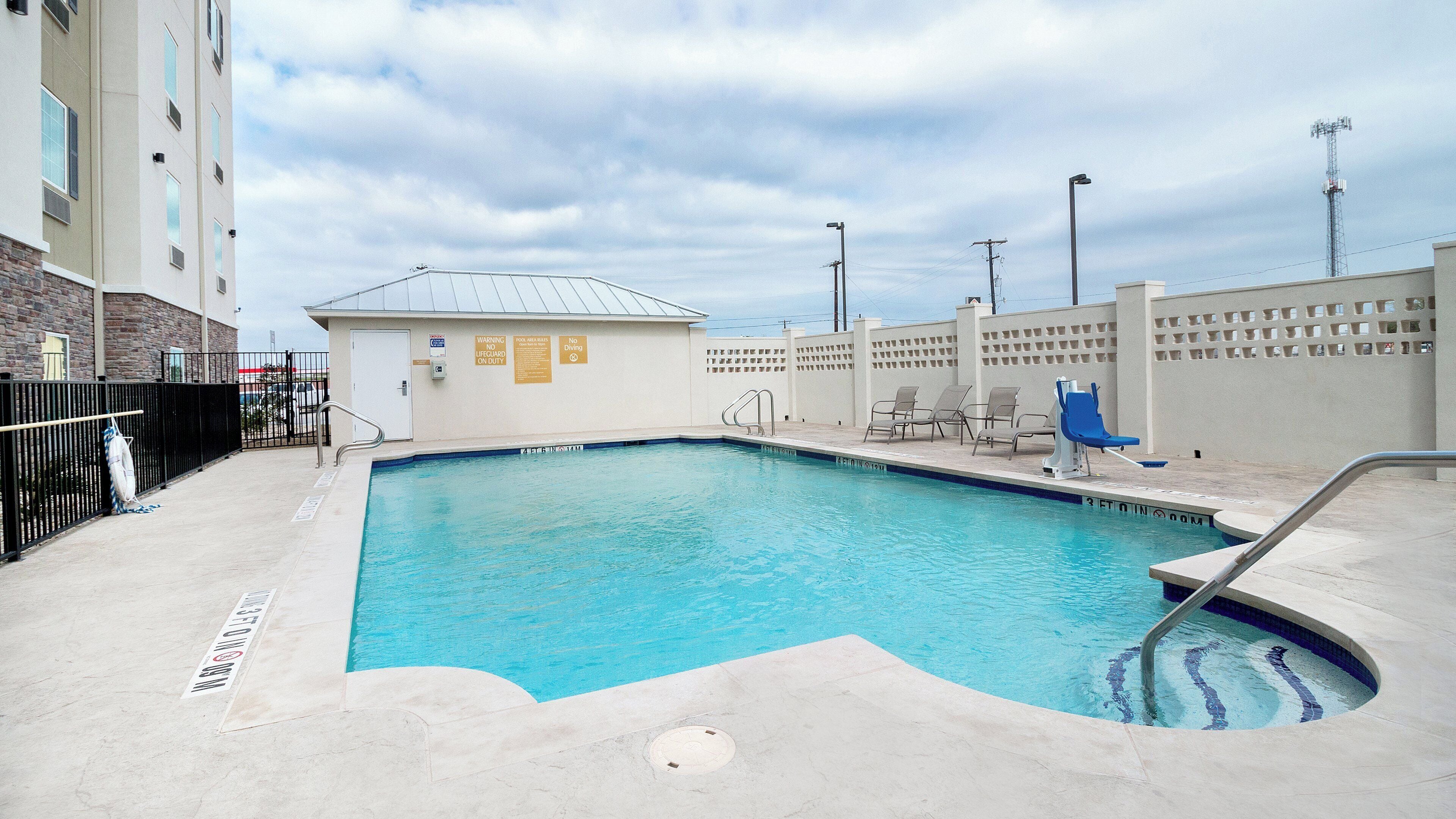 A swimming pool with a lifeguard station, lounge chairs, and a pool area with a view of the surrounding buildings.