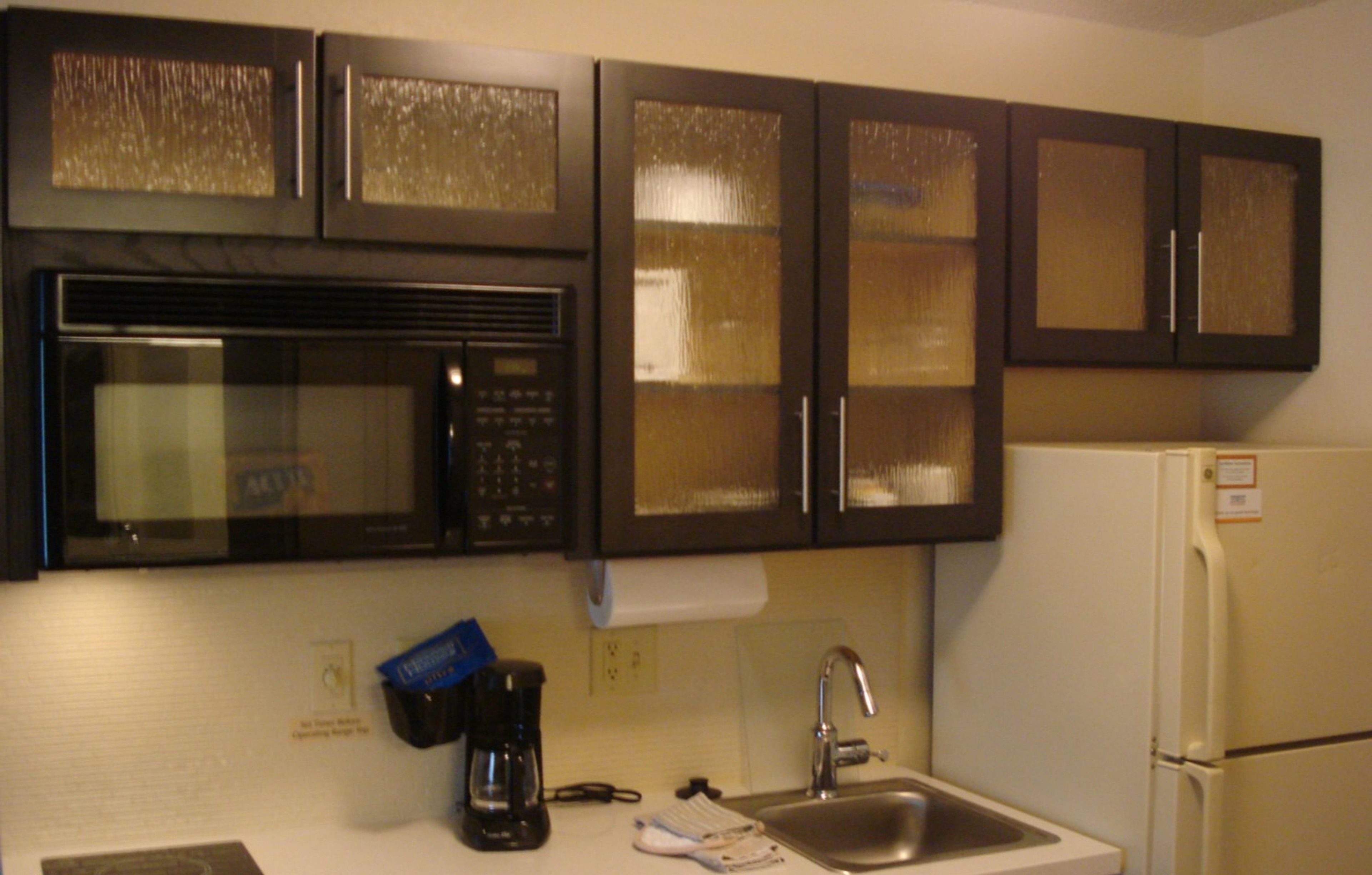 A kitchen with a microwave, coffee maker, sink, and a refrigerator.
