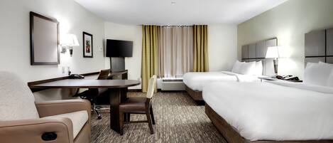 A hotel room with a desk, two beds, a TV, and a window with curtains.