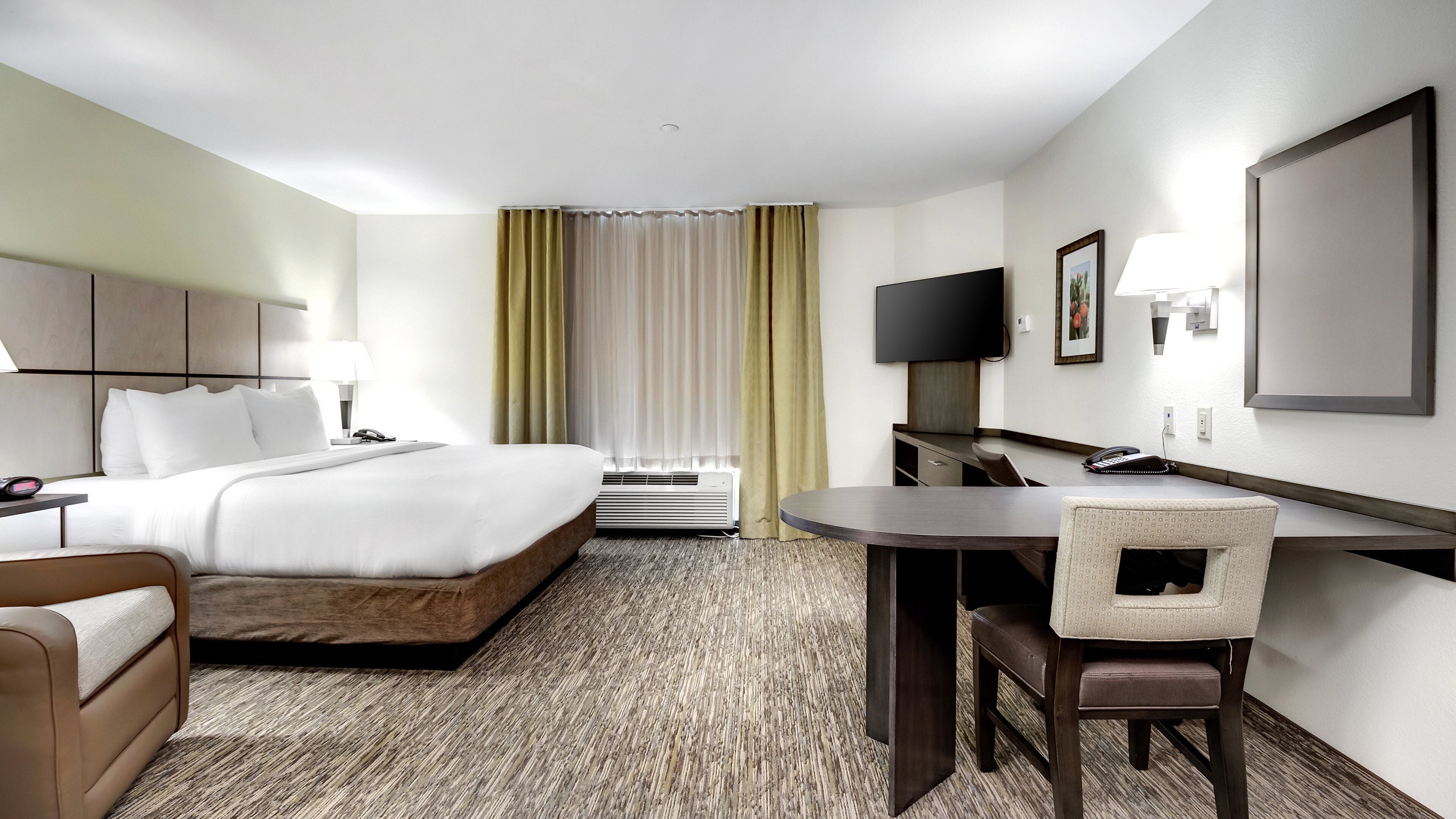 A hotel room with a bed, desk, chair, and a television.