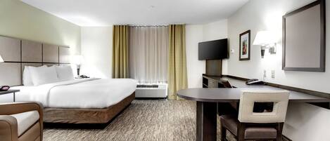 A hotel room with a bed, desk, chair, and a television.