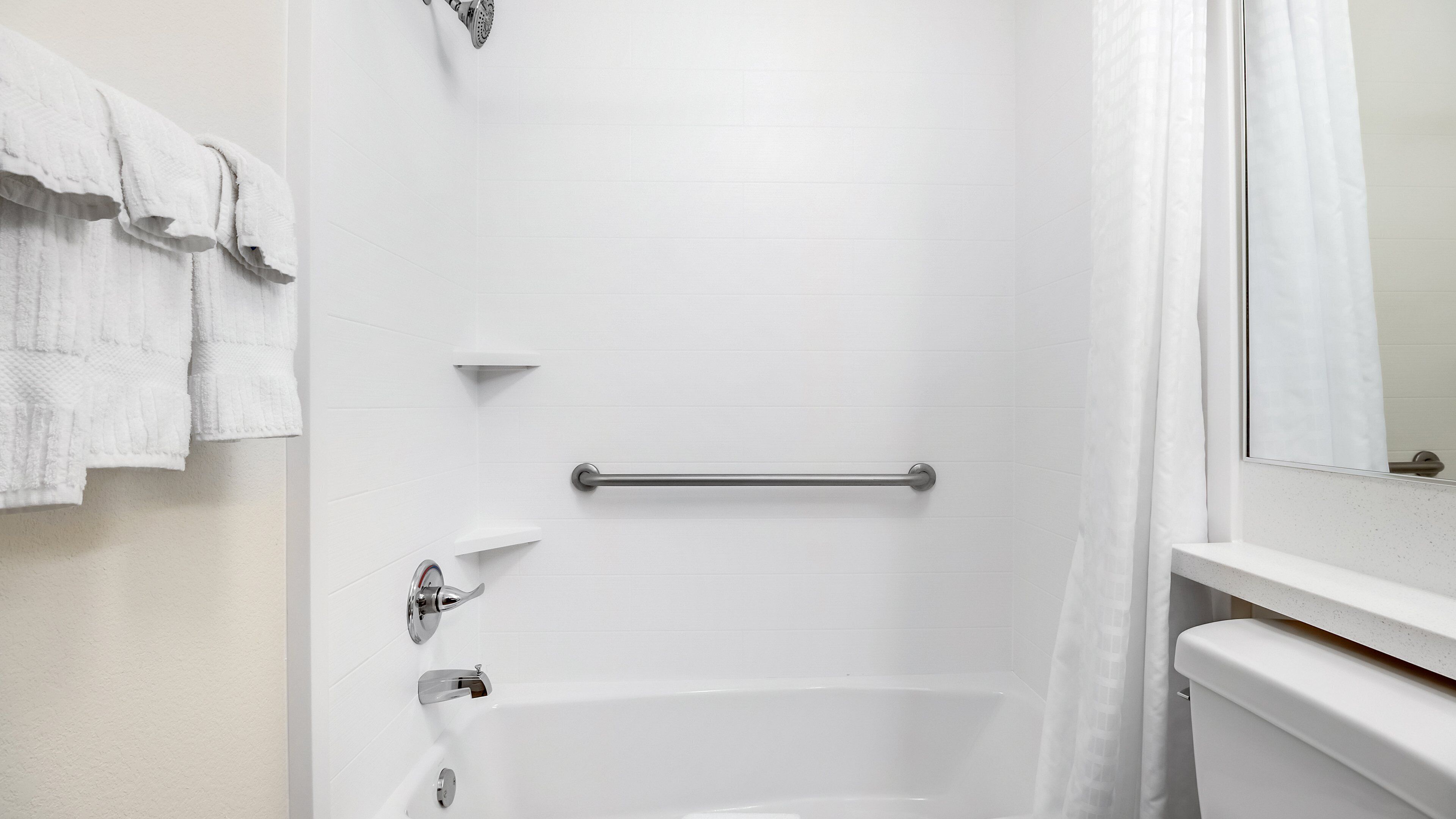 Une salle de bain équipée d’une baignoire, d’une douche, d’une barre d’appui et d’un porte-serviettes.