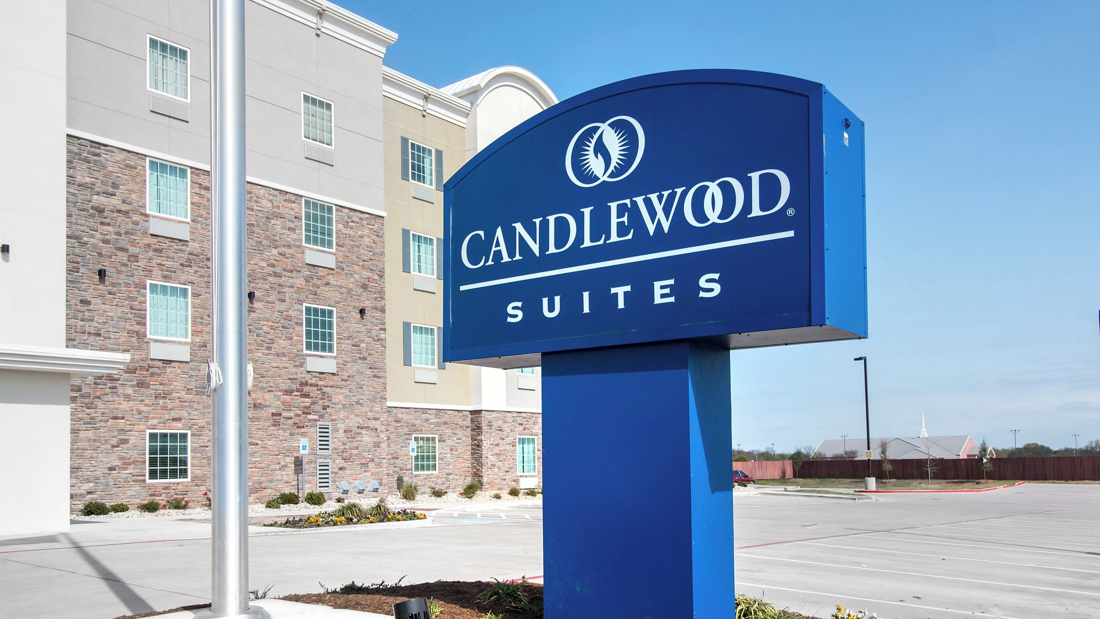 Schild für Candlewood Suites mit einem modernen Gebäude im Hintergrund.