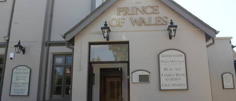 A building with a sign reading "PRINCE OF WALES" and another sign listing amenities like "GOOD FOOD," "REAL ALE," and "LIVE SPORTS."