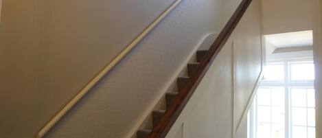 A staircase with a wooden handrail and a light-colored wall.