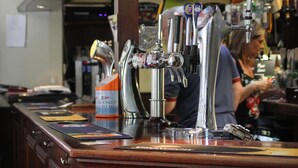 Un bar amb diverses aixetes de cervesa i un rellotge a la paret.
