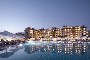 A hotel with a large pool, sun loungers, umbrellas, and a well-lit exterior. - Green Garden Resort & Spa Hotel (Alanya)