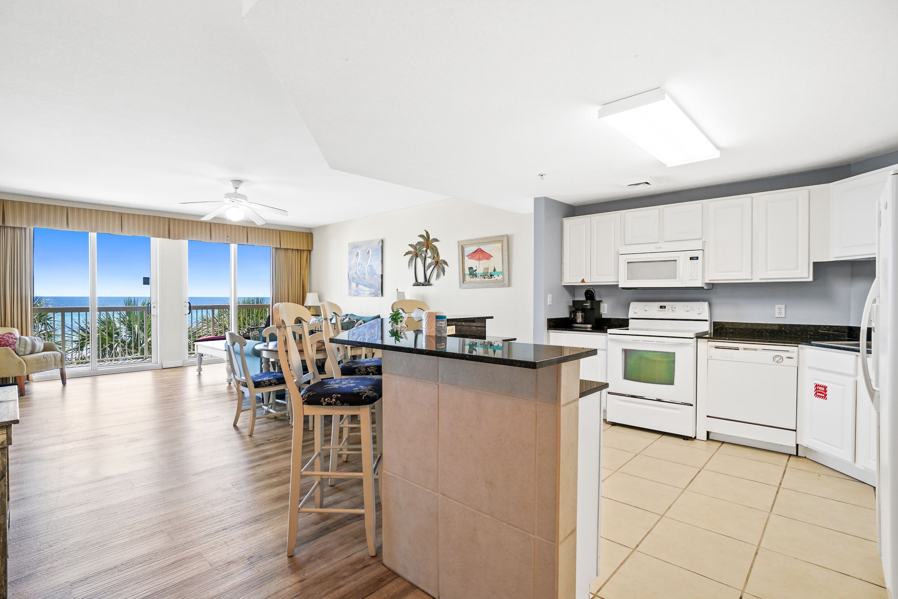 Una cocina moderna con armarios blancos, una isla central y un comedor con vistas.