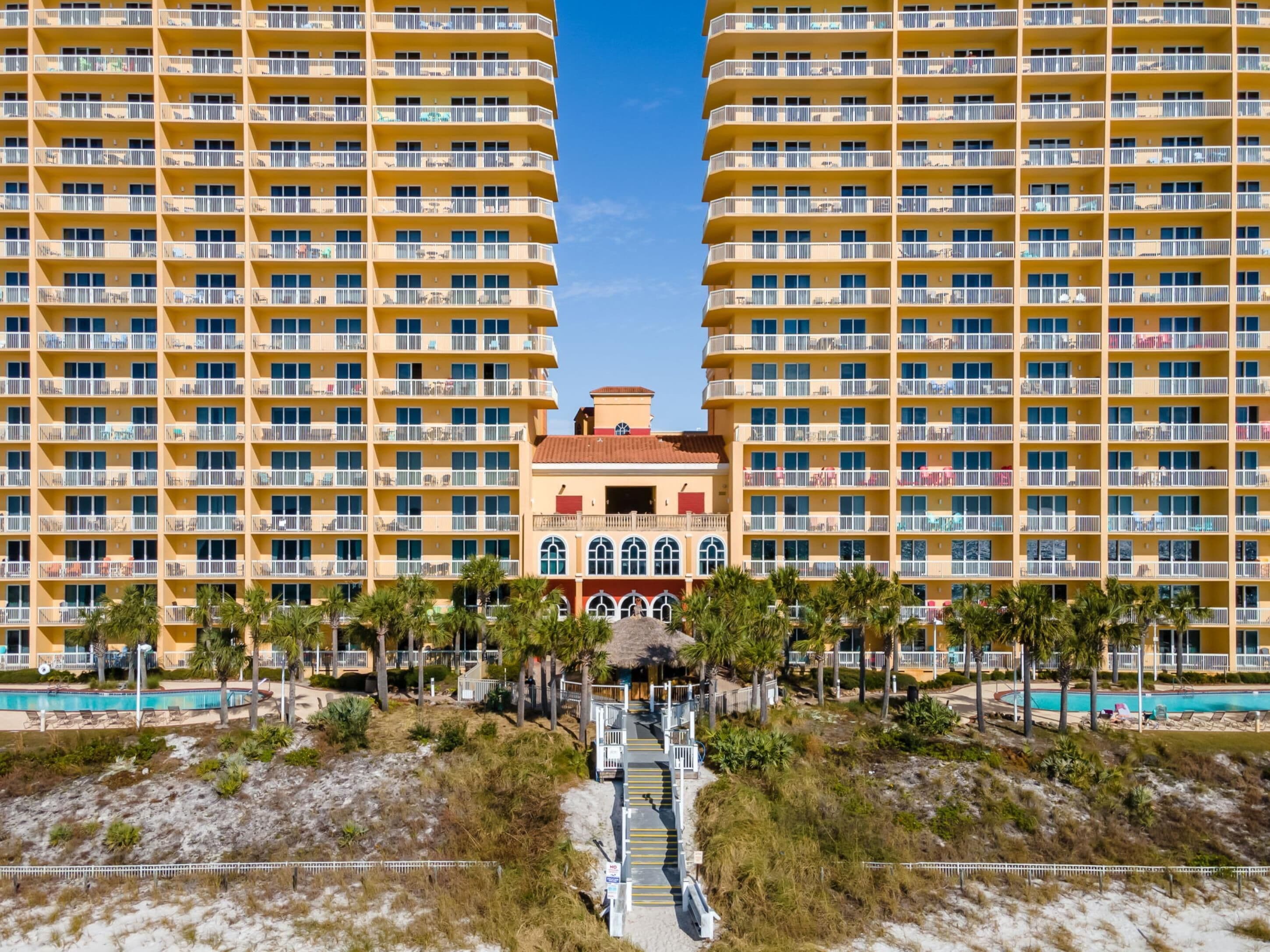 A high-rise hotel with multiple balconies, a central courtyard, and a pool area.