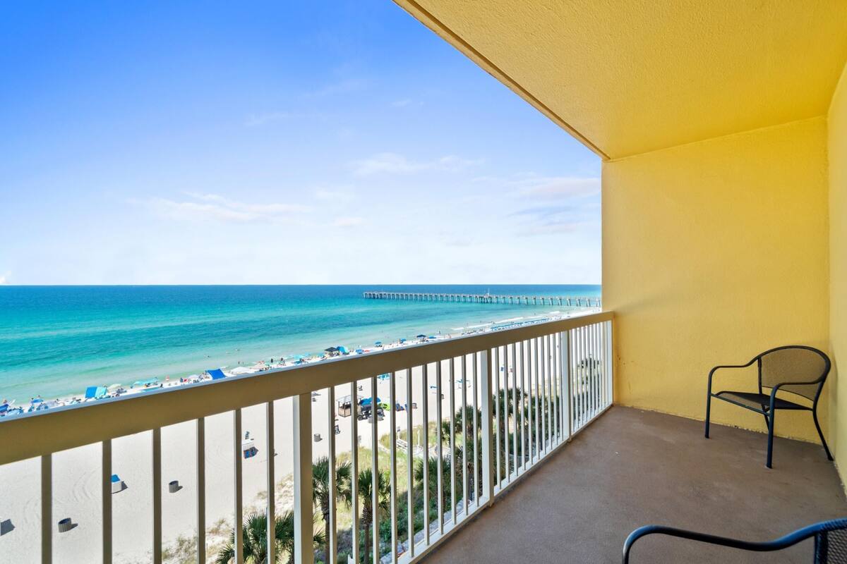 A balcony with a view of the beach and pier.