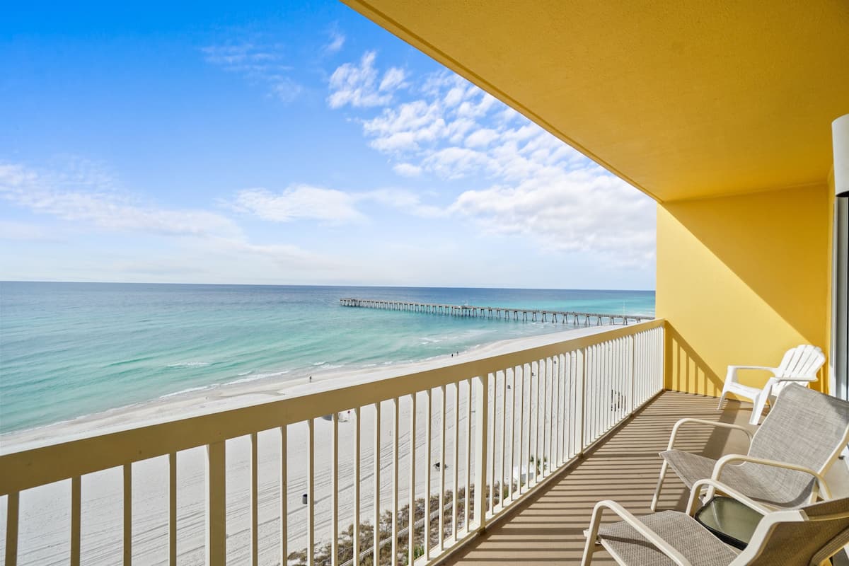A balcony with a view of the ocean and a pier.