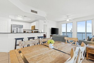Una cocina moderna con armarios blancos, un refrigerador de acero inoxidable y un televisor de pantalla plana.