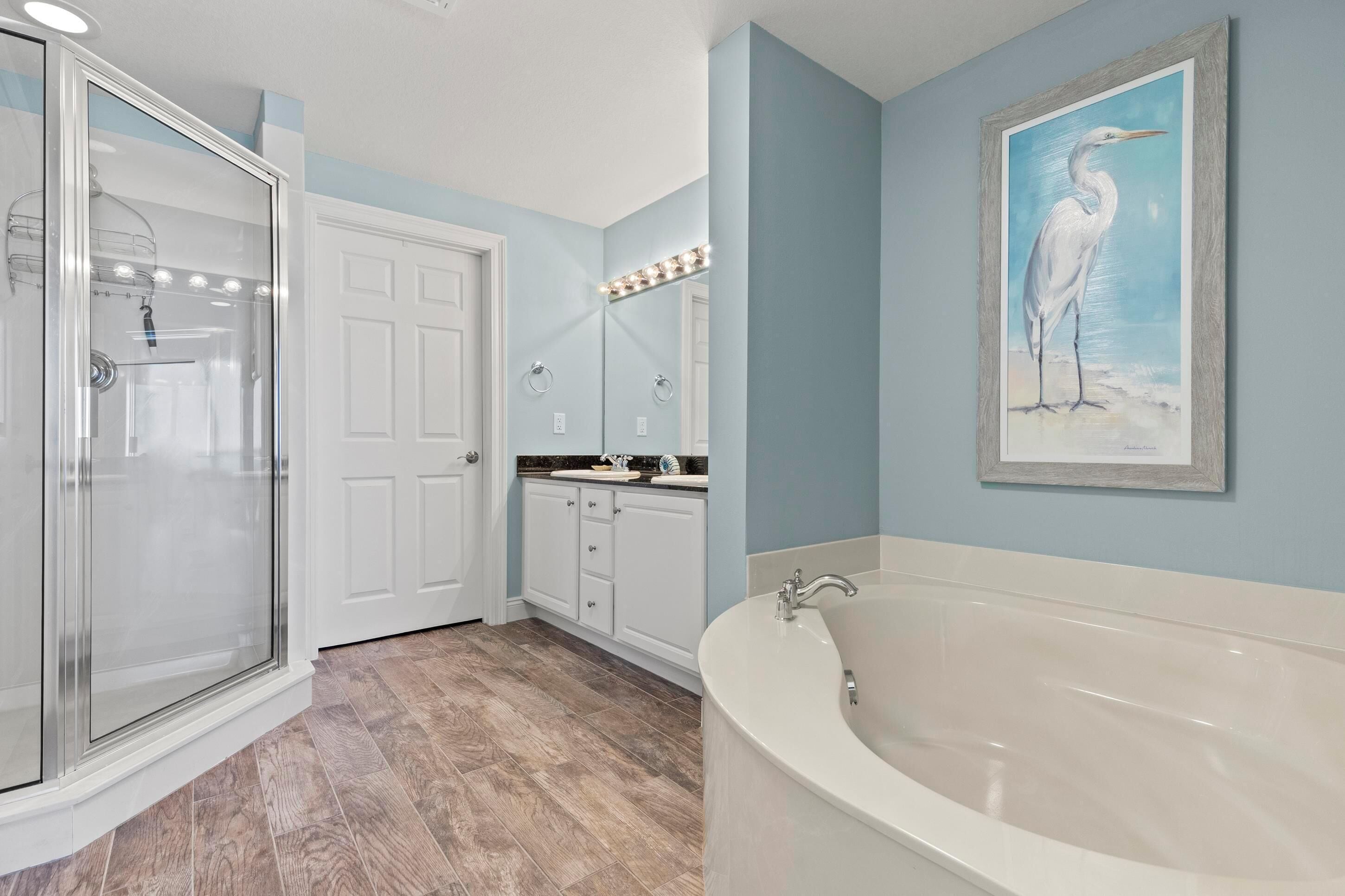 Une salle de bain avec une douche à l’italienne, une baignoire, un meuble-lavabo avec un miroir et un tableau encadré au mur.