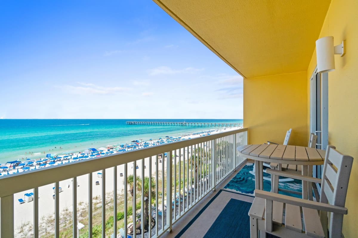 A balcony with a view of a beach and pier.