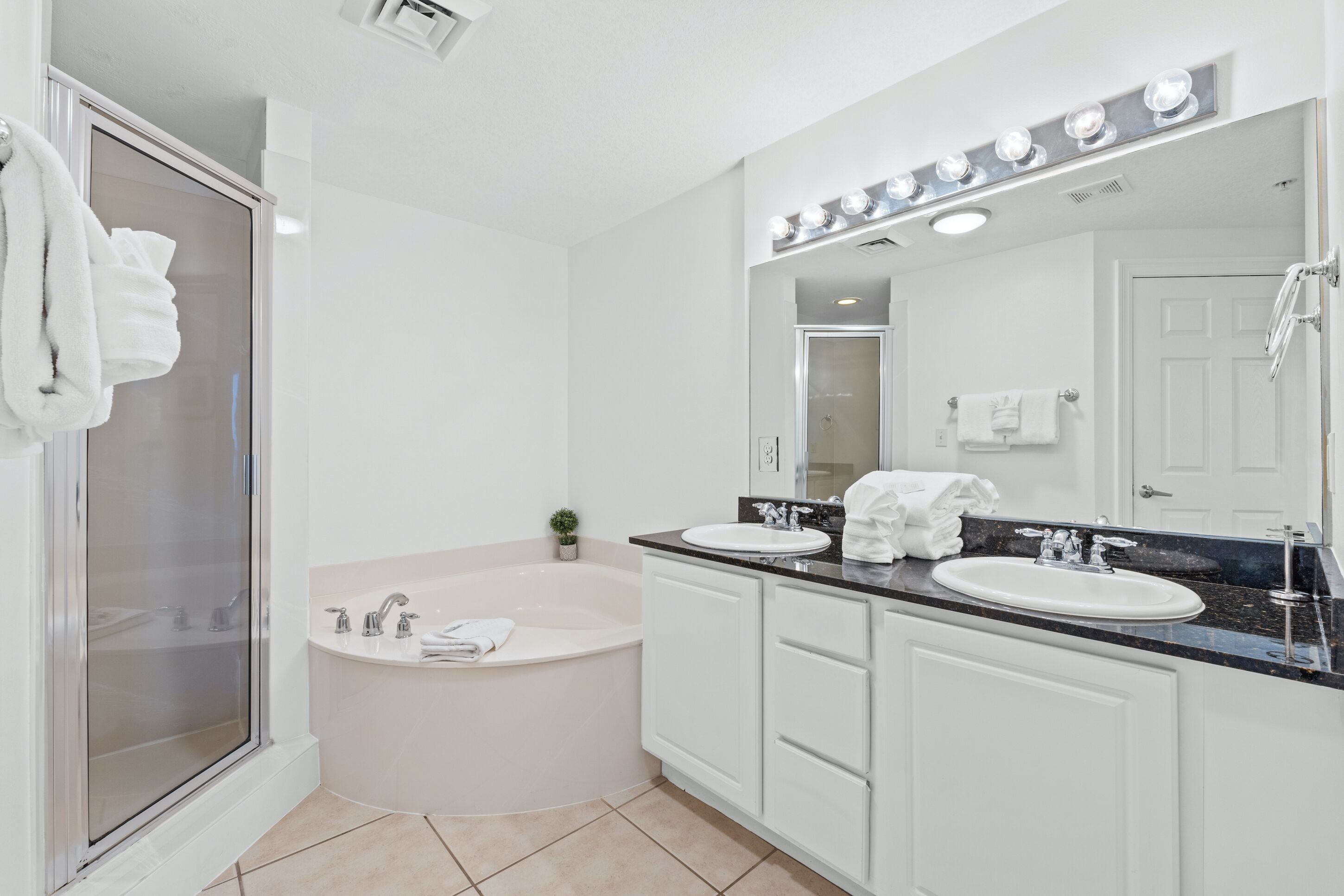 Une salle de bain moderne dotée d’une douche à parois de verre, d’une baignoire sur pieds et de deux vasques avec des plans de toilette.