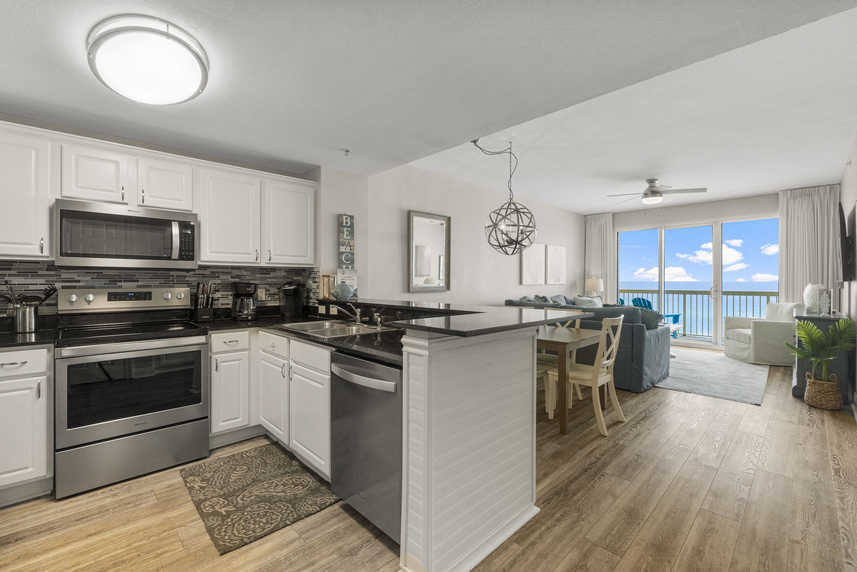 Una cocina moderna con gabinetes blancos, microondas integrado y una isla grande.