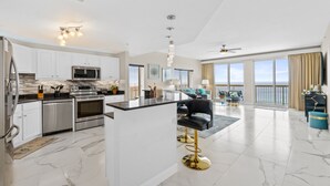 Una cocina moderna con armarios blancos, electrodomésticos de acero inoxidable y una isla central con taburetes de bar.