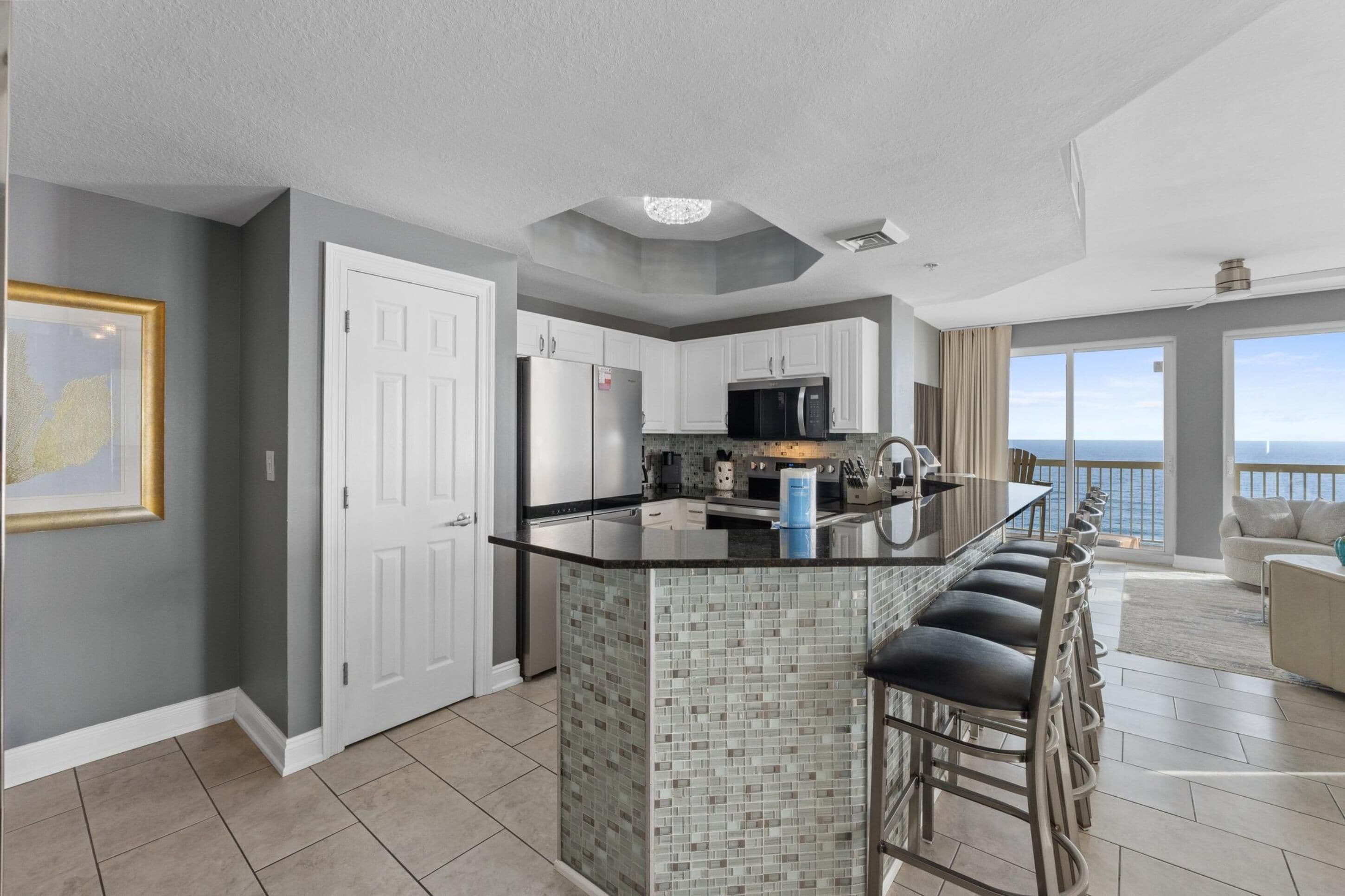 A modern kitchen with a central island, white cabinetry, and a view to the outside.