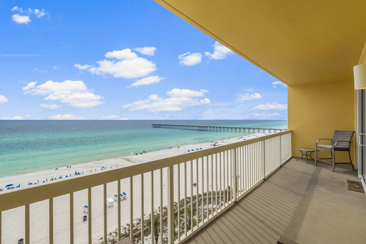 A balcony with a view of a beach and pier.