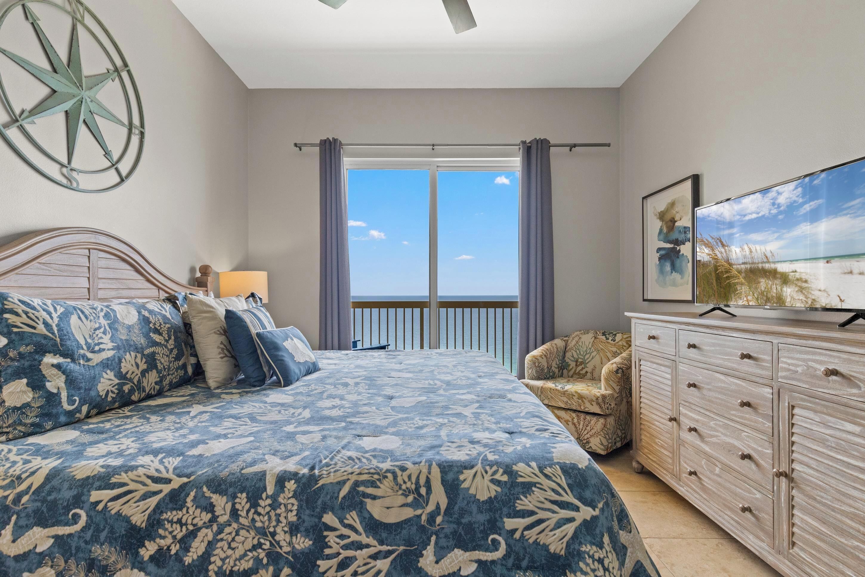 Une chambre à coucher comprenant un lit, une commode, une chaise, une grande fenêtre et une boussole en forme d’étoile fixée au mur.