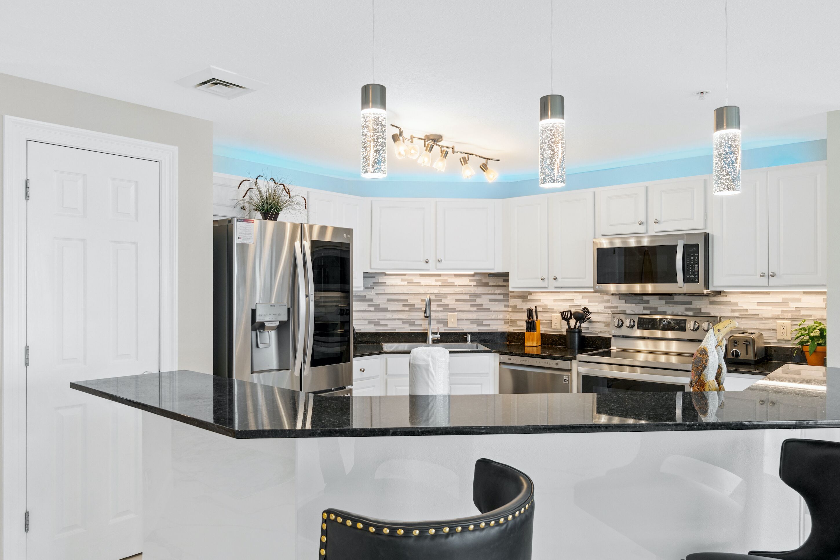 Cozinha moderna com ilha central, eletrodomésticos de aço inoxidável e iluminação pendente.