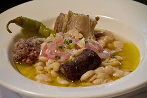 Un plato de comida con frijoles, carne y un chile verde.