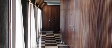 A hallway with a checkered floor, wooden paneling on the walls, and a series of doors along the corridor.