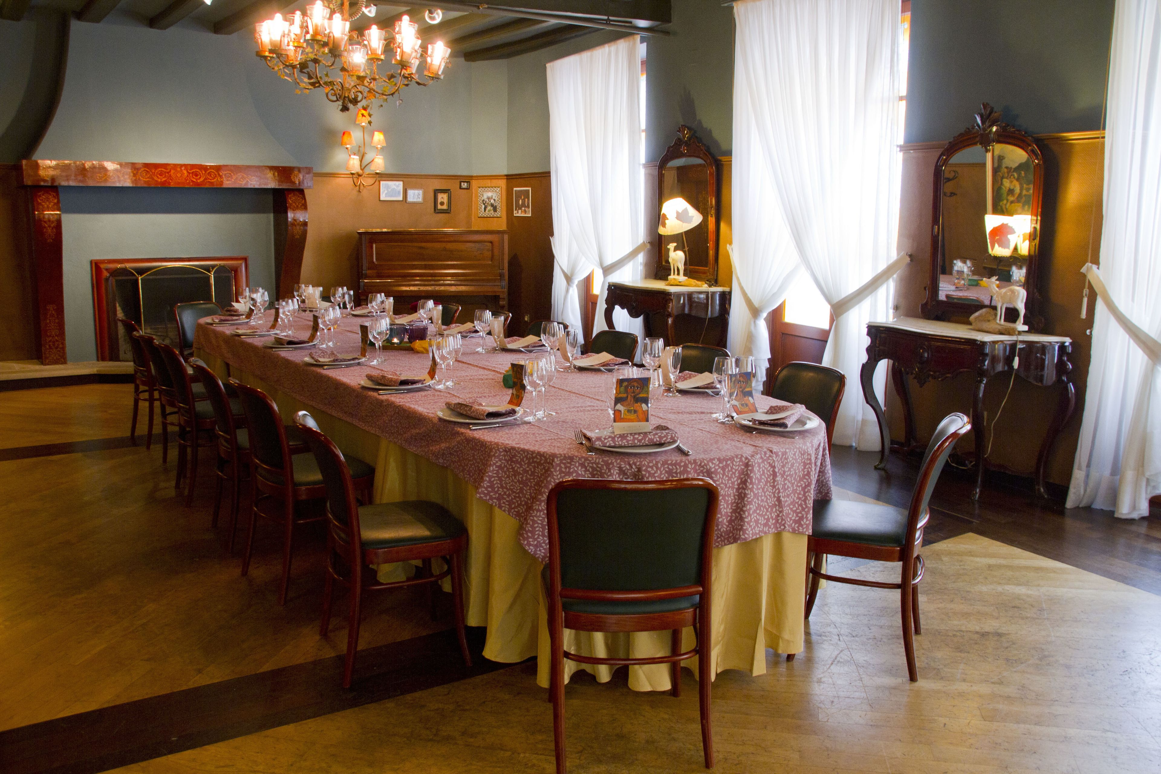 A dining room with a long table set for a meal, surrounded by chairs.
