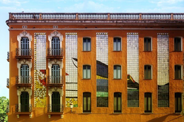 Un immeuble doté de nombreuses fenêtres et de balcons, avec une façade recouverte de carreaux et une balustrade décorative.