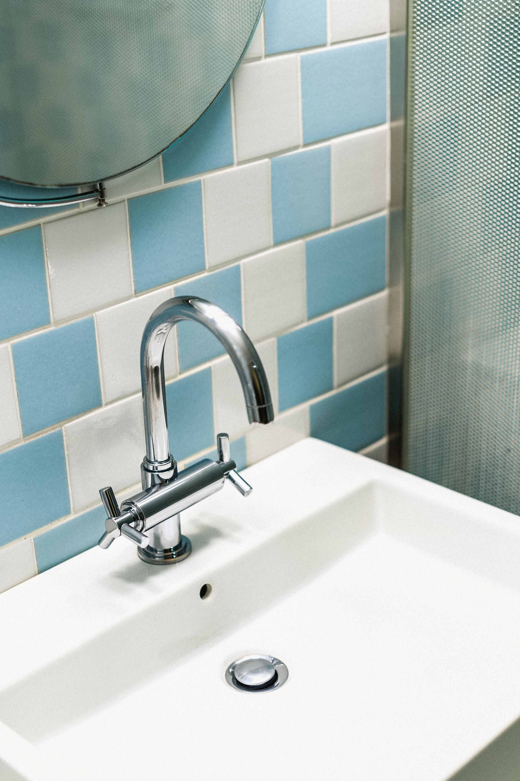 Un lavamanos con grifo cromado y un salpicadero de azulejos azules y blancos.