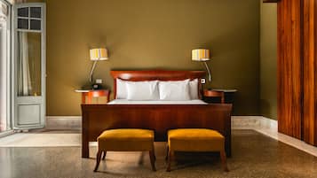 A bedroom with a wooden bed, two bedside lamps, and two matching ottomans.