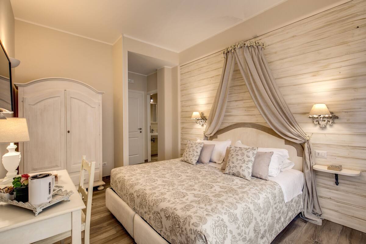 A bedroom with a bed, bedside lamps, a nightstand, and a wardrobe.
