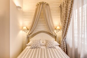 A bed with a canopy, two bedside lamps, and floral-patterned curtains. - Casa Mia Vaticano Guest House (Rome)