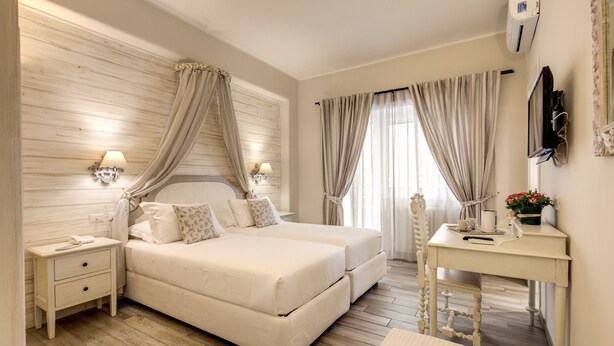 A bedroom with a double bed, bedside tables, a desk, and a mirror. - Casa Mia Vaticano Guest House (Rome)