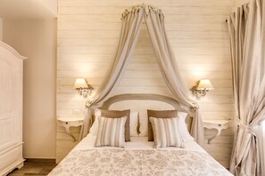 Une chambre à coucher avec un lit à baldaquin, deux tables de chevet avec des lampes et une tête de lit en bois.