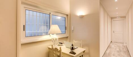 Ein Zimmer mit Fenster, Tisch mit Lampe, Laptop und Stuhl.