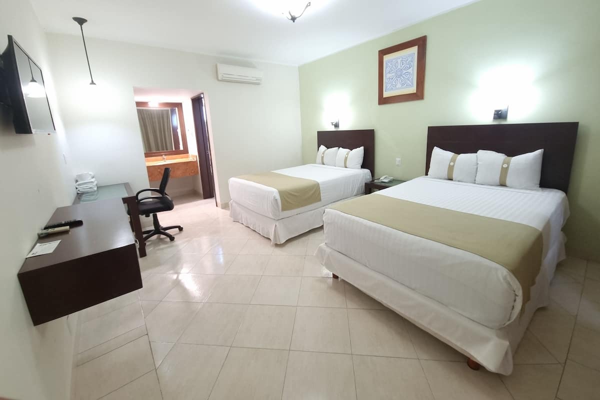 Habitación de hotel con dos camas, un escritorio, una silla, un teléfono y un espejo.