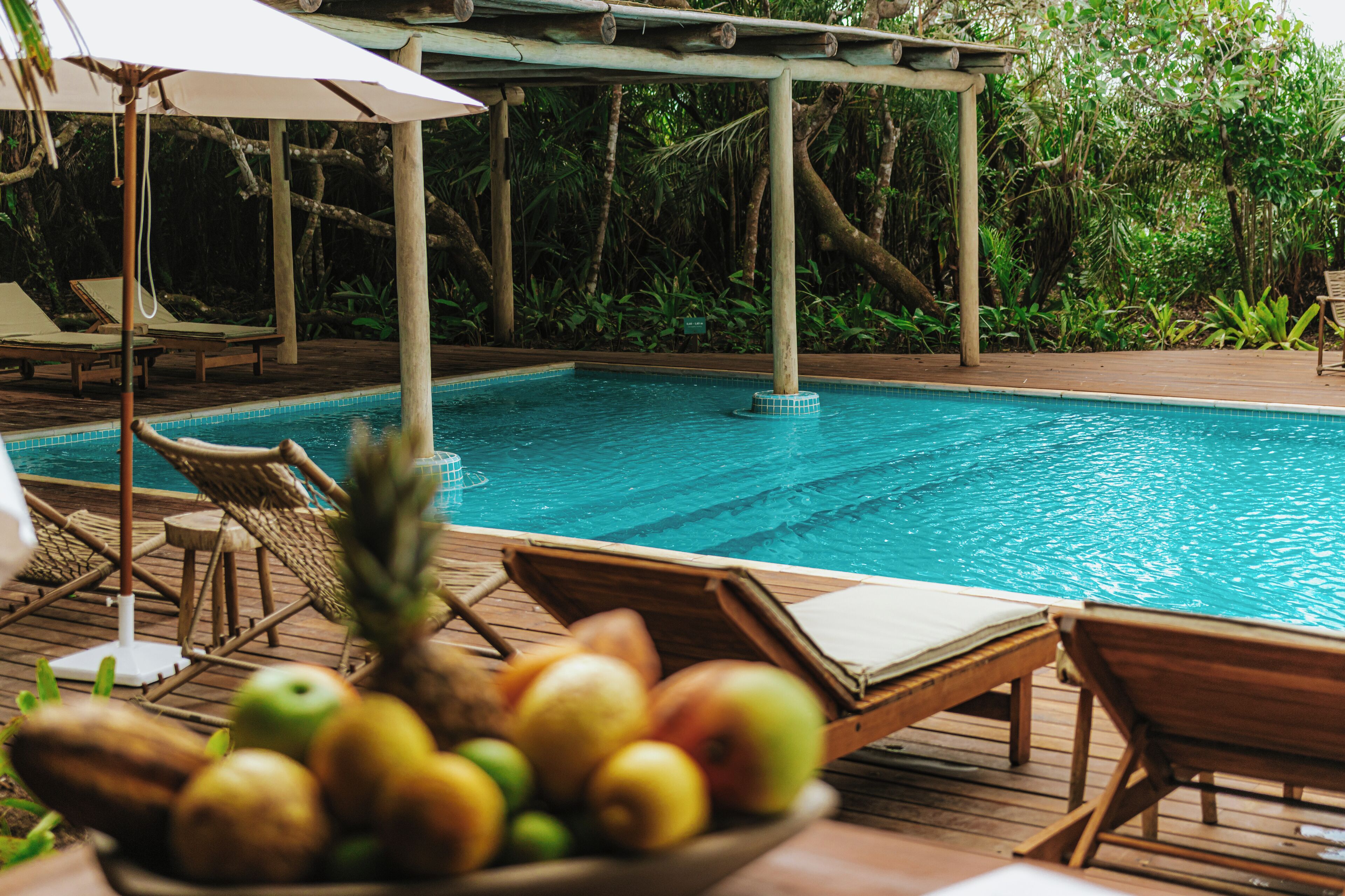 A pool area with lounge chairs and a fruit bowl.